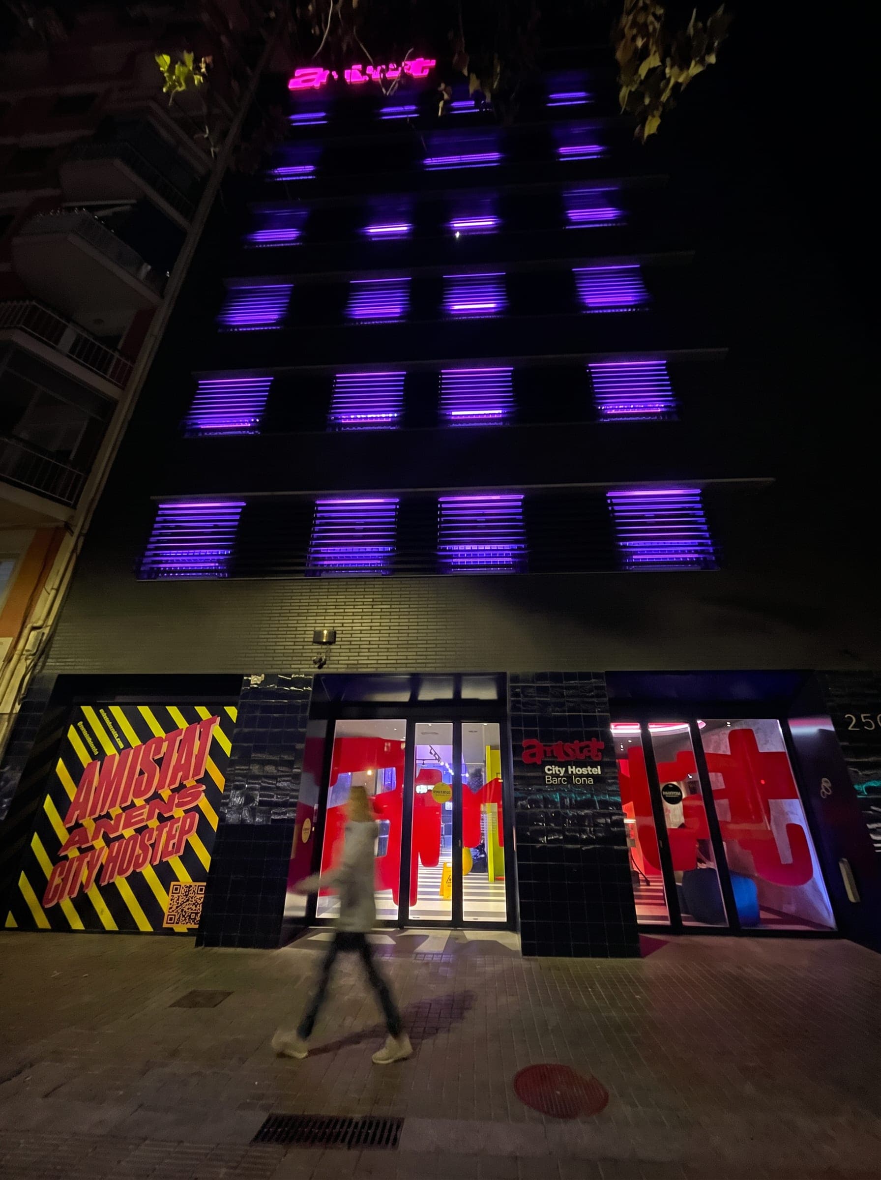 Hostel facade lit in purple across every floor