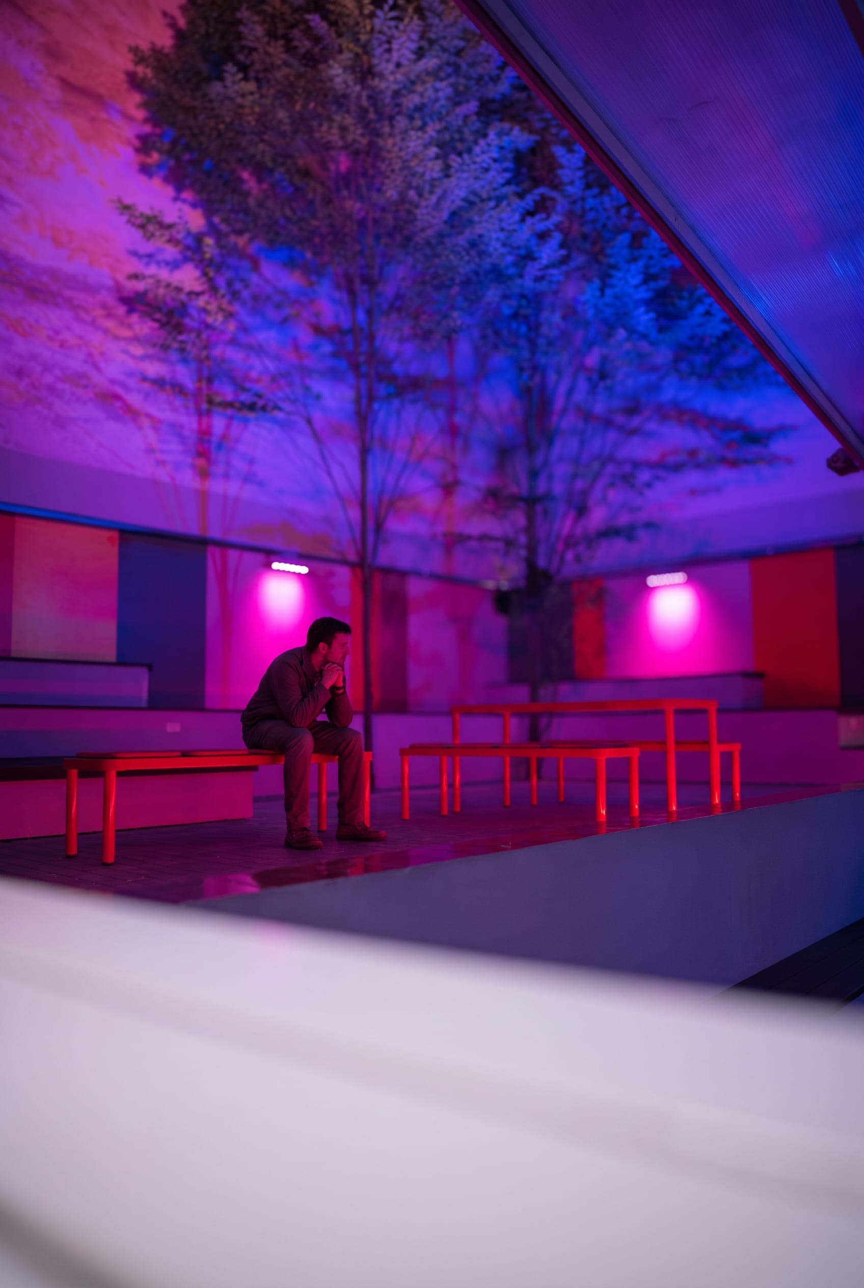 Guest sitting alone on a red bench in the courtyard