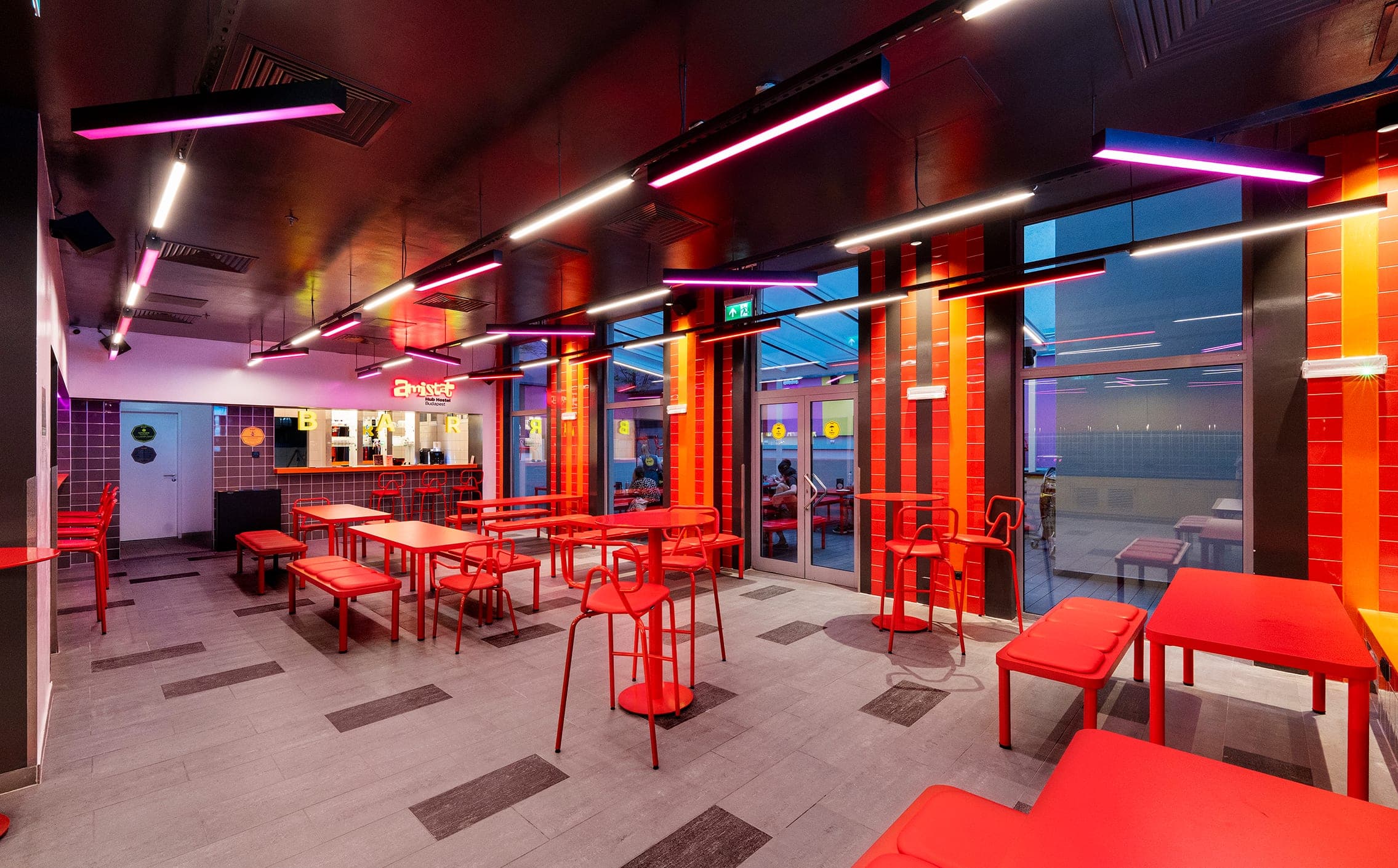 Dining hall with red tables under magenta and white light lines