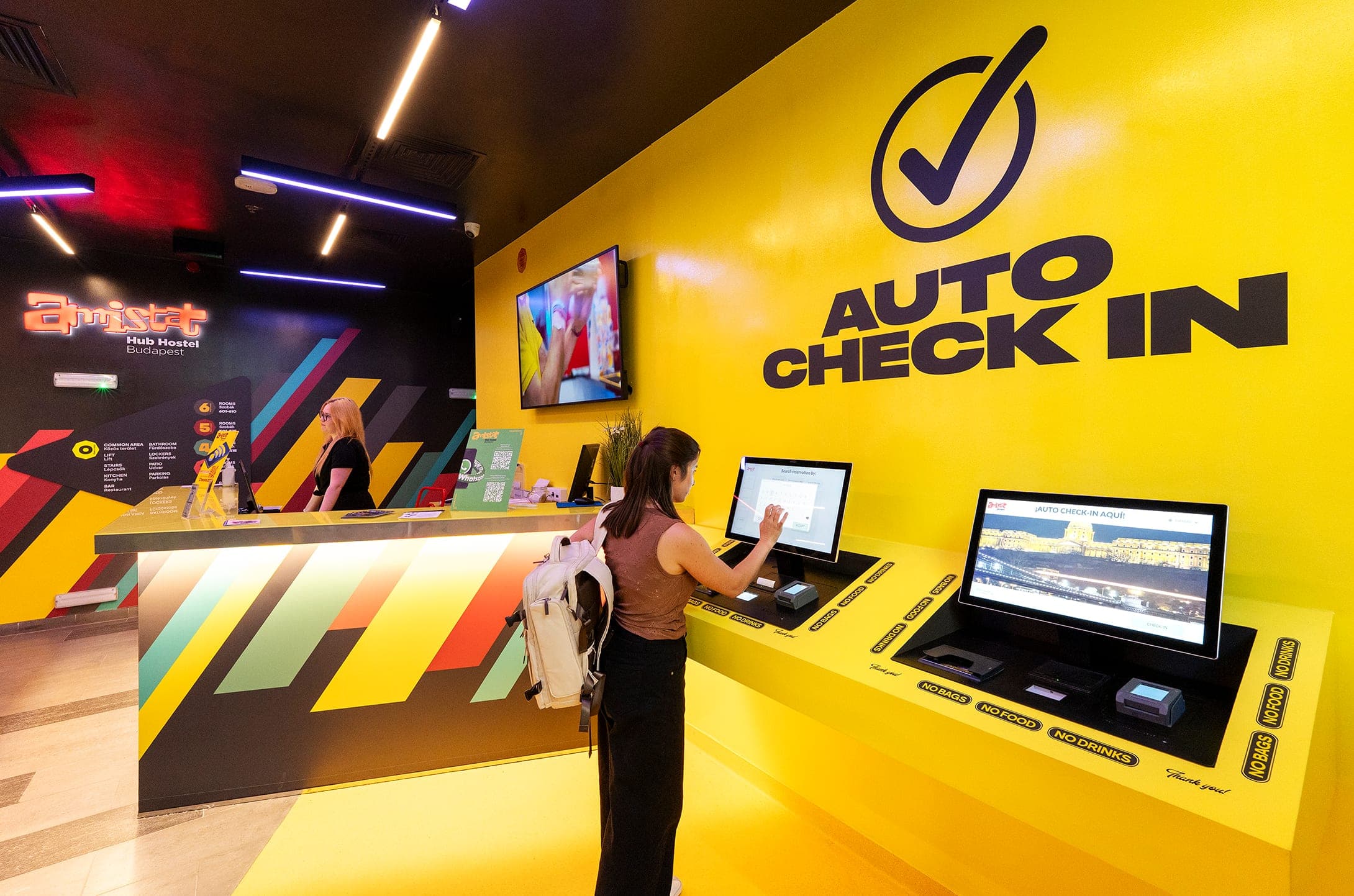 Guest using the auto check-in kiosks next to the yellow reception desk